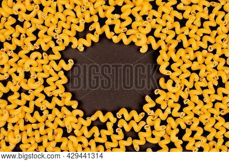 Italian Spiral Pasta On Black Background, Copy Space For Design Text. Bunch Of Helical Amori Texture