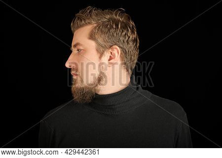 Cute Bearded Man, Half-face Portrait, Black Background. Young Guy In Black Polo Neck Sweater. Confid