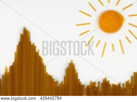 Sun In Mountains. Uncooked Spaghetti In Shape Of Hills And Egg As Sun. Travel Snack Concept. Isolate