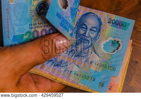 Male Hand Holds A Fan Of  Vietnames Dong Banknote, The Currency Of Vietnam.  Close Up Polymer Money