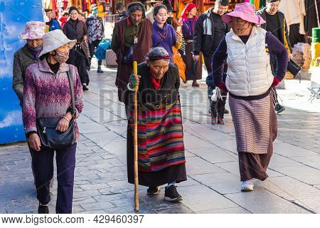 Lhasa, Tibet, China - November 15, 2020:  Old Tibetan Woman In Traditional Tibetan Clothes And Walki