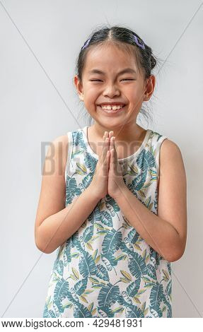 Portrait Asian Child Girl Is Greeting In Thailand Traditional Style That Called Sawatdee. Asian Gree