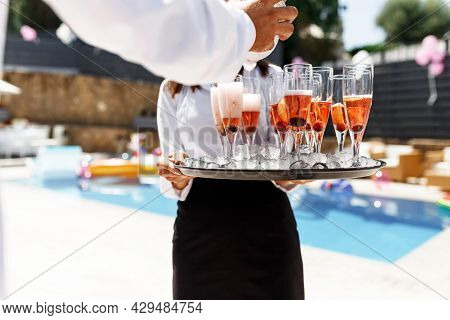 Midsection Of Waiter Pouring Champagne At Poolside.serving With Ice On A Tray. Swimming Pool Party C