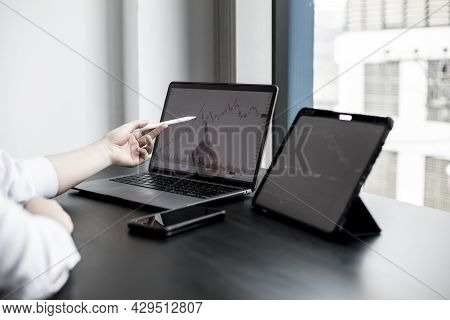 A Stock Investor Holding A Pen Pointing To A Laptop Screen Opens A Stock Chart Program To Read Stock