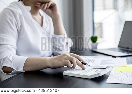 A Businesswoman Is Pressing A White Calculator, She Is Calculating The Numbers On The Company Financ