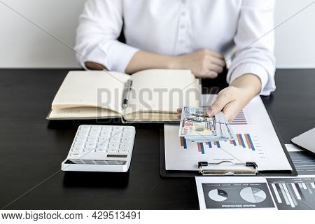 A Woman Pressing A White Calculator And Holding Money, She Is Keeping A Personal Account By Recordin