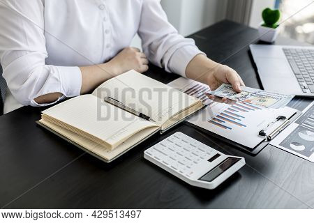 A Woman Pressing A White Calculator And Holding Money, She Is Keeping A Personal Account By Recordin