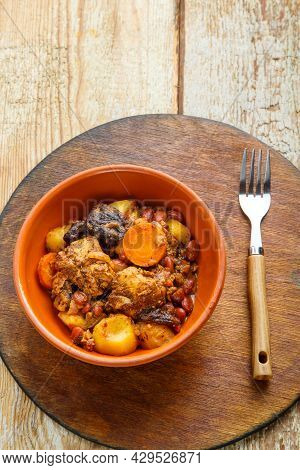 Jewish Dish Chelnt With Meat On The Table In A Plate On A Round Wooden Stand. Vertical Photo
