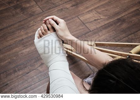A Woman Massages The Toes Of A Broken Leg With Her Hands. Top View Of A Broken Leg In A Plaster Cast