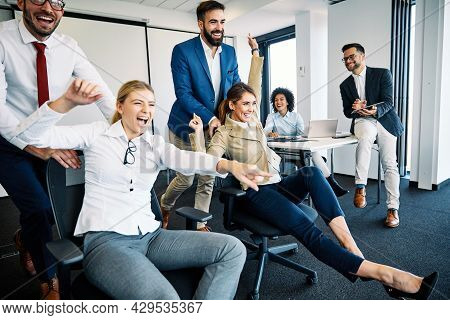 Young Business People Having Fun Pushing Chairs In The Office