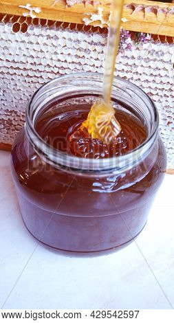 Jar Of Bee Honey On The Background Of The Frame With Honeycombs