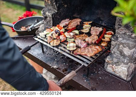 Man Cooking Meat On Barbecue Grill At Bbq Party
