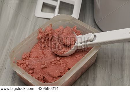 Homemade Cherry Ice Cream In A Plastic Container On The Table With An Ice Cream Spoon And An Ice Cre