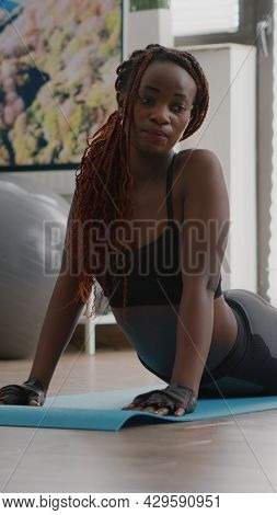 Flexible Black Woman Practicing Sport During Yoga Morning Workout Sitting On Fitness Map In Living R