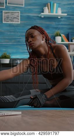 Woman With Dark Skin Doing Pilates Workout In Living Room Stretching Body Muscles On Yoga Map While 