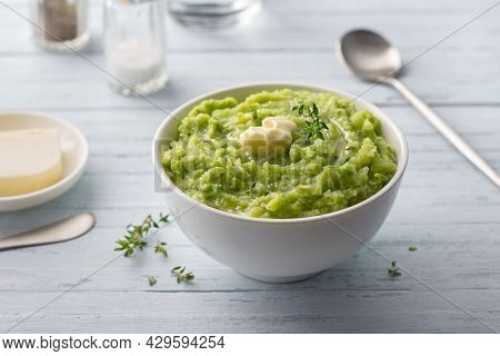 Delicate Mashed Potatoes With Green Peas, Flavored With Butter, Spices And Thyme On A Light Blue Bac