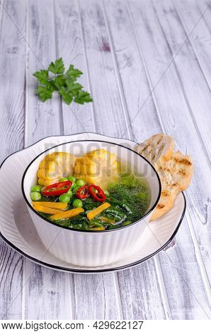 Vegetable Transparent Soup In A Ceramic Dish On A Wooden Background. Selective Focus.