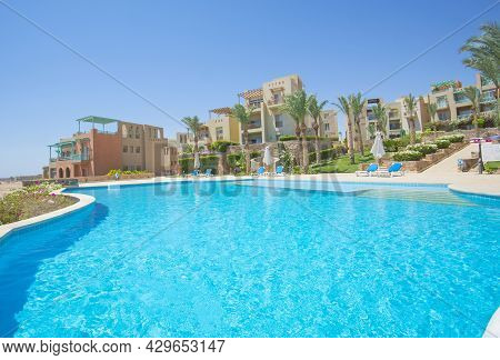 Panoramic View Of Large Outdoor Swimming Pool At A Luxury Tropical Hotel Resort With Palm Trees