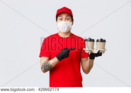 Excited Asian Delivery Man In Red Cap, Medical Mask And Gloves, Safely Deliver Your Beverege, Holdin