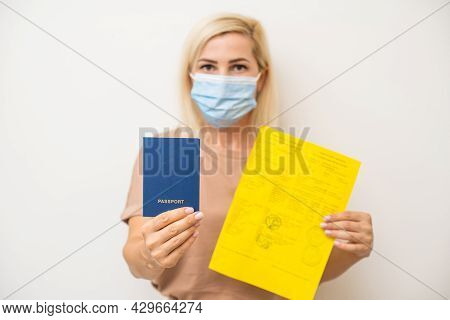 Woman With Medical Mask Holding Inernational Certificate Of The Vaccination. Adult Showing The Infor