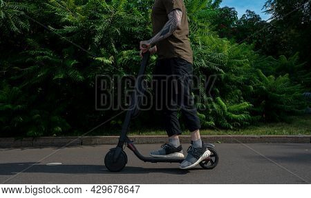Close Up Of Stylish Athletic Man Driving Electric Scooter Outdoors In Modern Park.