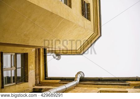 Bottom Up View Of The Sky And Rooftops Of The Old City. Roof Corner And Downspout On Gray Sky Backgr