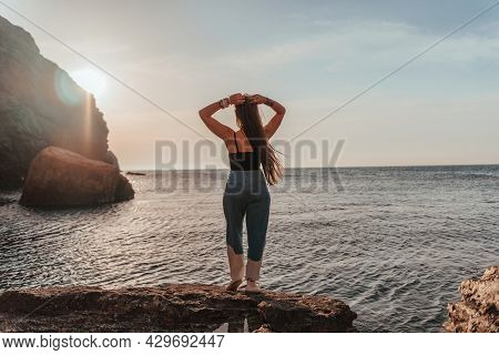 Young Woman With Long Hair In Black Swimsuit And Boho Style Braclets Practicing Outdoors On Yoga Mat