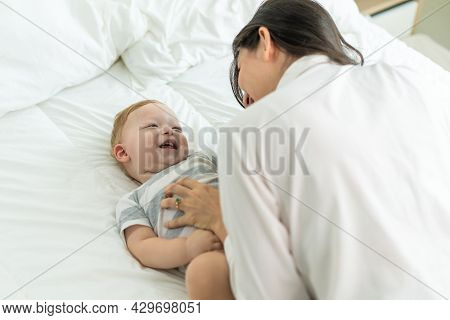 Caucasian Loving Mom Play With Cute Baby Boy Child On Bed In Bedroom. Happy Family, Attractive Beaut
