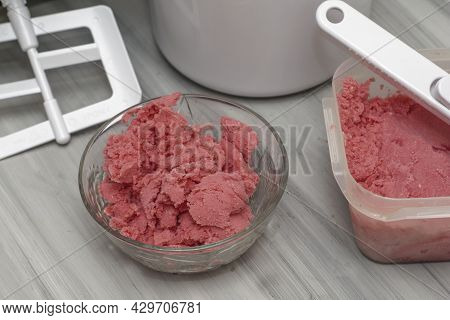 Homemade Cherry Ice Cream In A Glass Socket And A Plastic Container On The Table Next To An Ice Crea