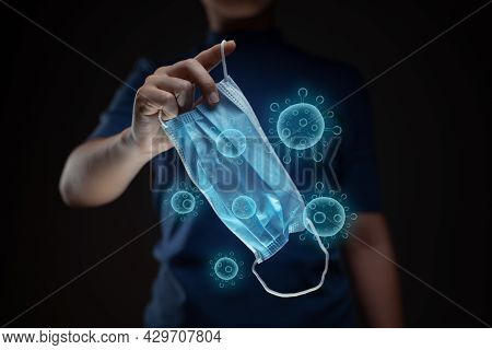 Close Up Shot Of Hands Holding Protective Face Mask With Virus Hologram Effect.