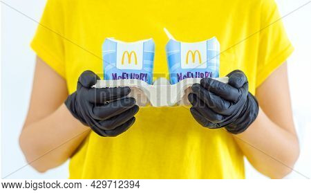 Woman In A Yellow T-short Holding An Ice Cream Mcflurry In Medical Gloves. Delivery Mccafe. Fast Foo
