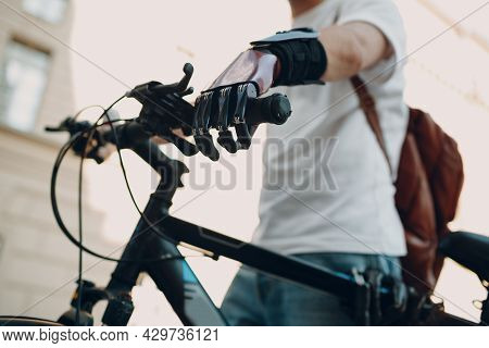 Young Disabled Man With Artificial Prosthetic Hand In Casual Clothes Riding Bike