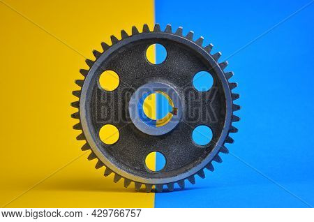 Metal Cogwheel On A Blue-yellow Background. Spare Parts.