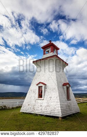 Anderson Hollow lighthouse by the Shepody River dam in Harvey, Bay of Fundy, New Brunswick, Canada. Summer day with rolling clouds. 