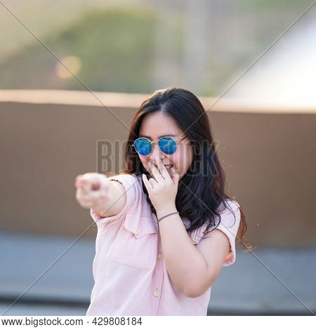 Asian Woman In The Pink Shirt Is Playing Finger Gun, Aim And Focus On It. She Relaxes And Smiles Bet