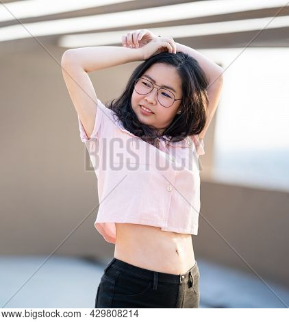 Beautiful Glasses Asian Woman Raise Her Hand Up And Poses For An Image At Outdoor Rooftop Building E