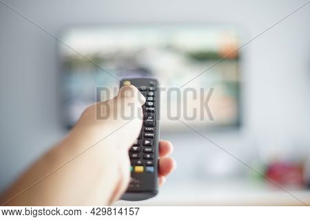 Out Of Focus And Blurry Close Up Male Hand Holding Remote Control Pointing To Change The Programme T