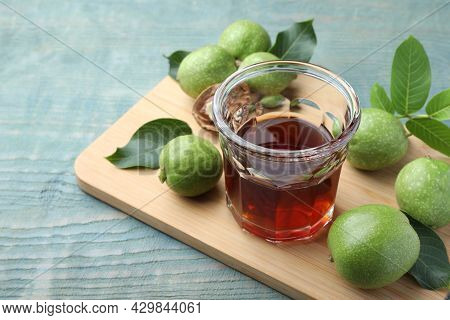 Delicious Liqueur And Green Walnuts On Light Blue Wooden Table