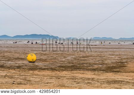 Taean, South Korea; July 30,2021: Yellow Inflatable Buoy On Beach During Low Tide With People In Oce