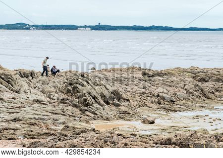 Taean, South Korea; July 30,2021: Unidentified People On Stony Outcropping Of Beach At Low Tide