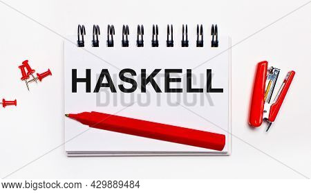 On A Light Background, A Red Pen, A Red Stapler, Red Paper Clips And A Notebook With The Inscription