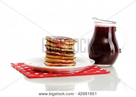 หวาน pancakes บนแผ่นกับนมข้นที่แยกต่างหากบนพื้นสีขาว