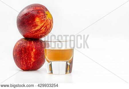 Display Of Small Shot Glass Of Organic Apple Cider Vinegar With The Mother, Stacks Of Two Red Apples