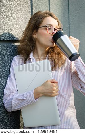 Female Portrait Of Young Woman With Silver Laptop And Cup Of Coffee Waiting For A Meeting Near Dark 
