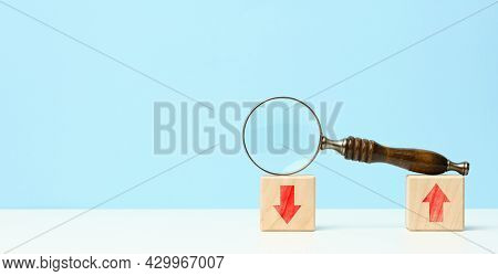 Wooden Magnifier On Wooden Cubes With Up And Down Arrows. Market Fluctuations Concept, Currency Vola