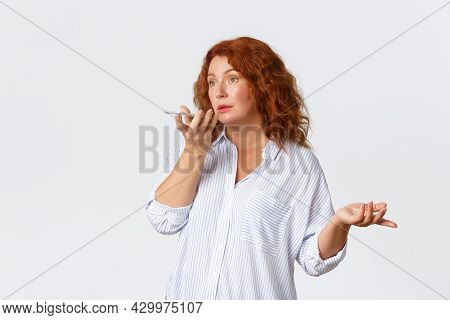 Technology And Communcation Concept. Portrait Of Confused Middle-aged Redhead Woman Record Voice Mes