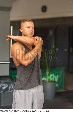 Fitness Man Warming Up In Gym. Male Doing Warm Up Stretching Workout On Gym Background.portrait Of A