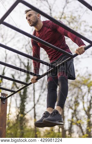 Active Man Doing Pullups While Exercising Outdoors In A Street Workout Park