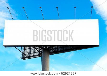 Wide white background of illuminated big blank billboard over cloudy blue sky with sparse clouds