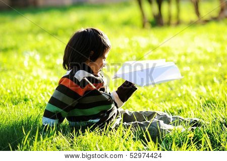Happy kid enjoying sunny late summer and autumn day in nature on green grass